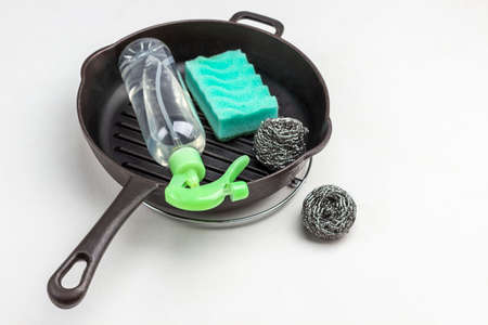 Spray bottle and scrub buds in frying pan. White background. Top viewの写真素材