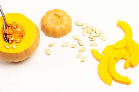 Spoon in pumpkin pulp. Peeling pumpkin slices and seeds on table. White background. Top viewの写真素材