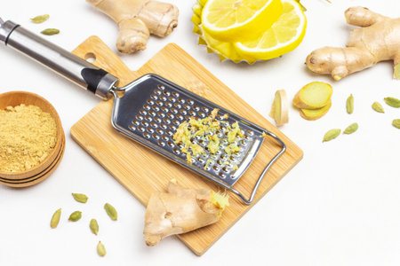 Grater with grated ginger .. Ginger root and lemon on table. White background. Top view