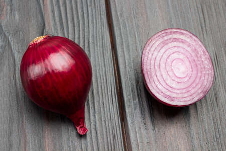 Onion halve and whole head of purple onion on table. Dark wooden background. Top viewの写真素材