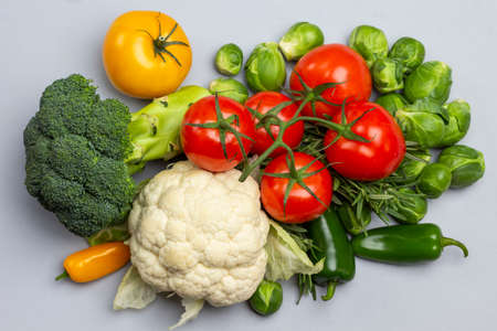 Cauliflower, broccoli and a branch of red tomatoes. Flat lay. Gray background.の写真素材