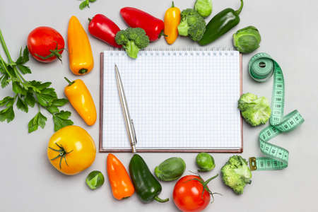 Notepad and pen, measuring tape and vegetables on table. Flat lay. Gray backgroundの写真素材