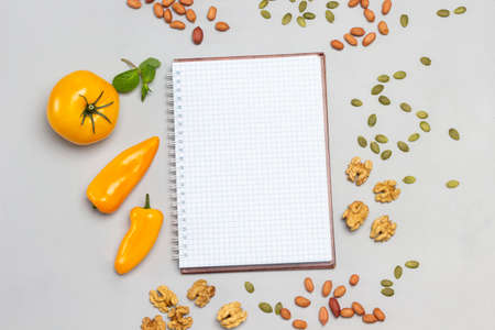 Notepad, nuts and yellow vegetables on table. Flat lay. Gray backgroundの写真素材