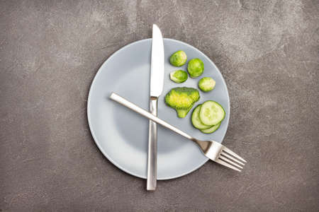 Broccoli and Brussels sprouts on gray plate. Knife and fork. Diet food concept. Flat lay. Black background. Copy spaceの写真素材