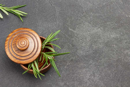 Sprigs of rosemary in wooden bowl. Black background. Top view. Copy spaceの写真素材