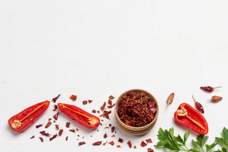 Dry paprika petals in bowl, halves of red peppers, and dry pepper pods. Flat lay. White background. Copy space.の写真素材