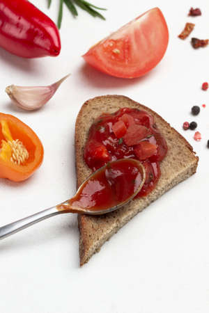 Tomato sauce sandwich and spoon. Red pepper pod, tomato wedge and allspice on table. Close up. White background. Top viewの写真素材