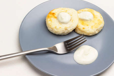 Cottage cheese pancakes with yogurt and fork on gray plate. White background. Top view.の写真素材