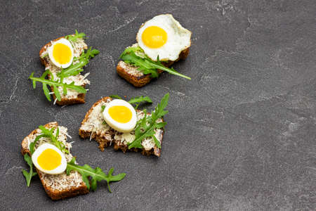Toast with greens and boiled quail eggs. Copy space. Flat lay. Black background.の写真素材