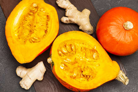 Halved pumpkin and ginger root. Whole orange pumpkin. Top view. Black backgroundの写真素材