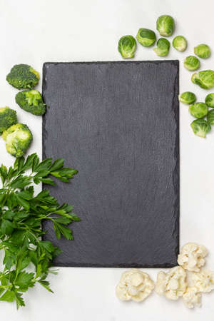 Sprig of parsley and different types of cabbage. Black board. Diet food concept. White background. Flat layの写真素材