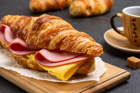 Croissant with ham and cheese on board. Close up. Black background.の写真素材