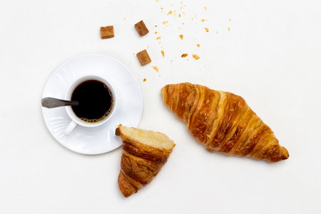 Cup of coffee and brown sugar. Croissants on table. Flat lay. White background.の写真素材