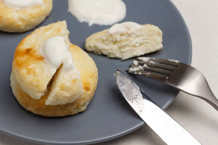 Cheesecakes with sour cream, fork and knife on gray plate. Top view. White backgroundの写真素材