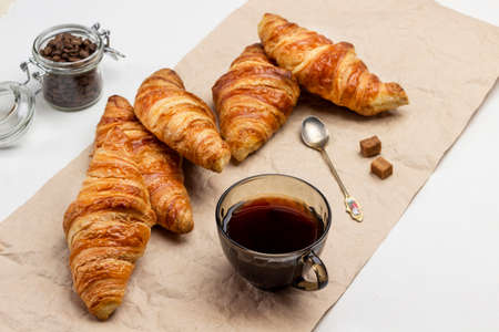 Croissants and cup of coffee on paper. Jar with coffee grains. Top view. White background.の写真素材