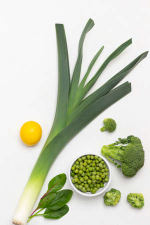 Leek, broccoli and green peas in bowl, lemon. flat lay. white backgroundの写真素材