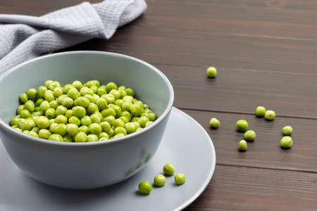 Fresh green peas in gray bowl. Gray napkin. copyspace. top view. wooden background.の写真素材