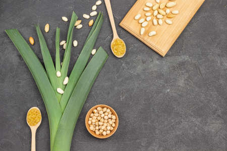 Leek and nuts in bowl and on wooden board. Bulgur in spoon. copyspace. flat lay. Black background.の写真素材