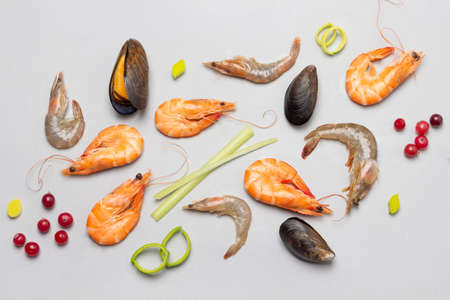 Shrimps and mussels with berries and herbs on gray background. top viewの写真素材