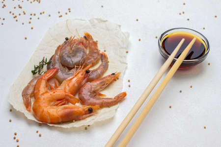 Soy sauce in glass bowl and chopsticks. Shrimps on paper. top view. white backgroundの写真素材