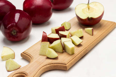 Chopped apples on cutting board. Ripe red apples on table. close up. white backgroundの写真素材