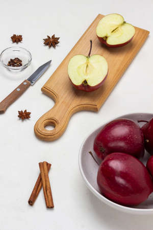 Apple halves on cutting board. Apples in bowl. Cinnamon sticks, star anise and knife on table. top view. white backgroundの写真素材
