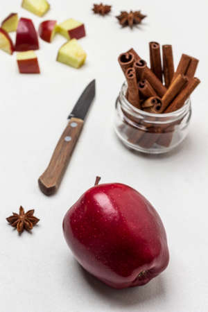 Ripe red apple on table. Cinnamon sticks in glass jar. Chopped apples and knife on table. top view. white backgroundの写真素材