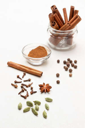 Cardamom, cloves and star anise on the table. Cinnamon sticks in a glass jar. top view. white backgroundの写真素材