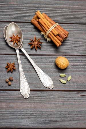 Two metal spoons and star anise. The cinnamon sticks are tied into bundle. flat lay. Dark wooden background.の写真素材