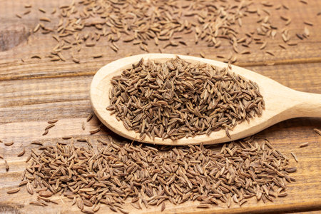 Cumin seeds in wooden spoon. close up. top view. wooden backgroundの写真素材