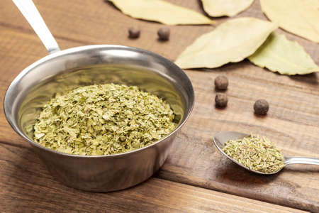 Dry cilantro in metal bowl. Dry rosemary in spoon. Bay leaf on table. top view. wooden backgroundの写真素材
