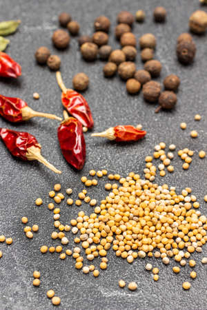 Mustard seeds, dry red pepper pods and allspice on table. top view. black backgroundの写真素材