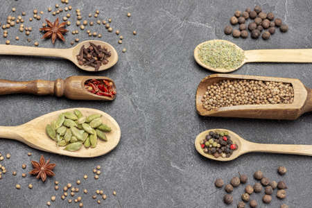 Dry spices in wooden spoons and scoops. Allspice, star anise and mustard seeds on table. copyspace. flat lay. black backgroundの写真素材