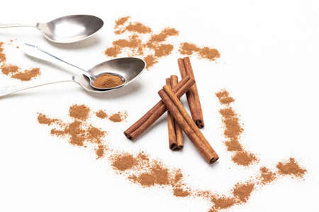 Cinnamon sticks among ground cinnamon, metal spoons on table. top view. white backgroundの写真素材