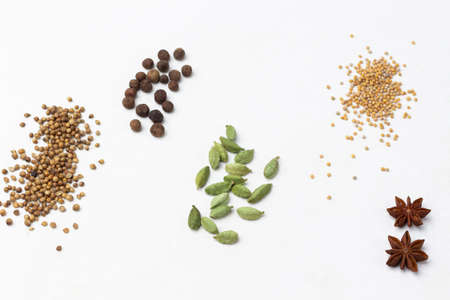Dry spices: mustard, coriander and cardamom seeds, allspice and star anise on white. copyspace. flat lay.の写真素材