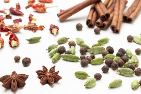 Allspice among cardamom seeds, star anise and cinnamon sticks. close up. top view. white backgroundの写真素材
