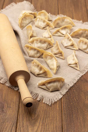 Raw gyoza dumplings and rolling pin on linen napkin. top view. wooden backgroundの写真素材