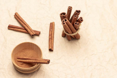 Ground cinnamon in wooden bowl. Cinnamon sticks tied with thread. copyspace. flat lay. brown background.の写真素材