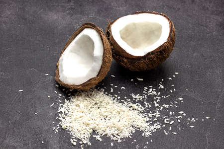 Two halves of coconut and coconut flakes on black background. top viewの写真素材
