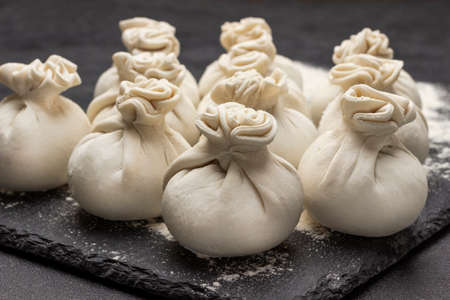 Raw khinkali dumplings on stone board. close up. black backgroundの写真素材