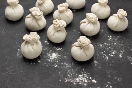Raw khinkali dumplings and flour on table. copyspace. top view. black backgroundの写真素材