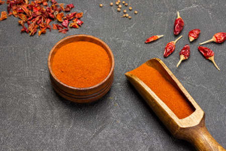 Ground paprika in scoop and wooden bowl. Peppers on table. close up. flat lay. black backgroundの写真素材