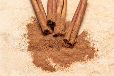 Cinnamon sticks on ground cinnamon. top view. Beige paper backgroundの写真素材