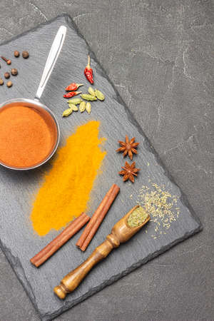 Dry spices in wooden scoop. Ground turmeric in metal bowl and paprika on table. Cinnamon sticks, star anise and cardamom. copyspace. flat lay. black backgroundの写真素材