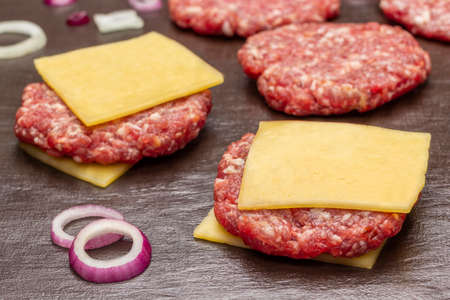 Raw beef burgers with cheese on brown background. top view. close upの写真素材