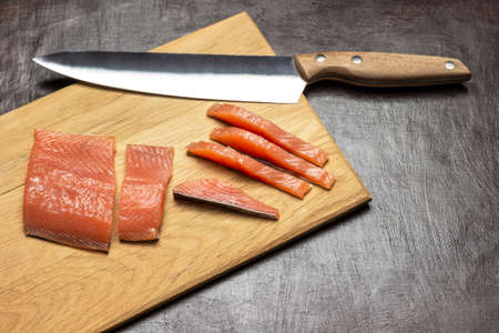 Sliced salmon and knife on cutting board. copyspace. top view. brown backgroundの写真素材