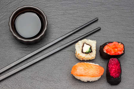 Sushi and soy sauce in a bowl, chopsticks. flat lay. Black background.の写真素材