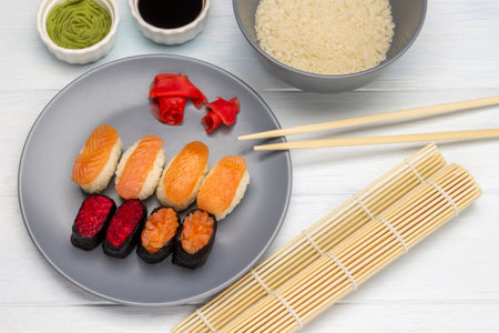 Bamboo mat and sushi set on a gray plate. Rice in a gray bowl. flat lay. white background.の写真素材