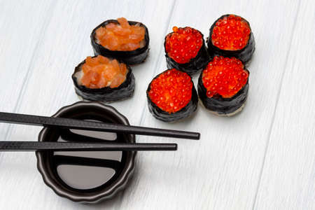 Sushi with caviar and salmon and soy sauce in a bowl, chopsticks. top view. white background.の写真素材
