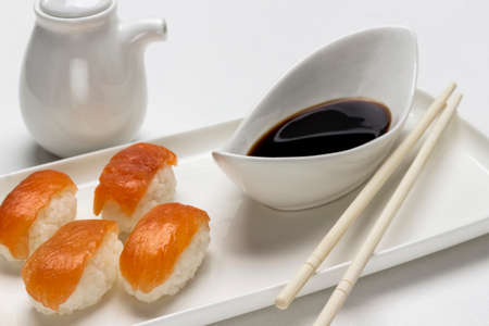 Sushi with salmon, soy sauce in white bowl, gravy boat and chopsticks. top view. white backgroundの写真素材